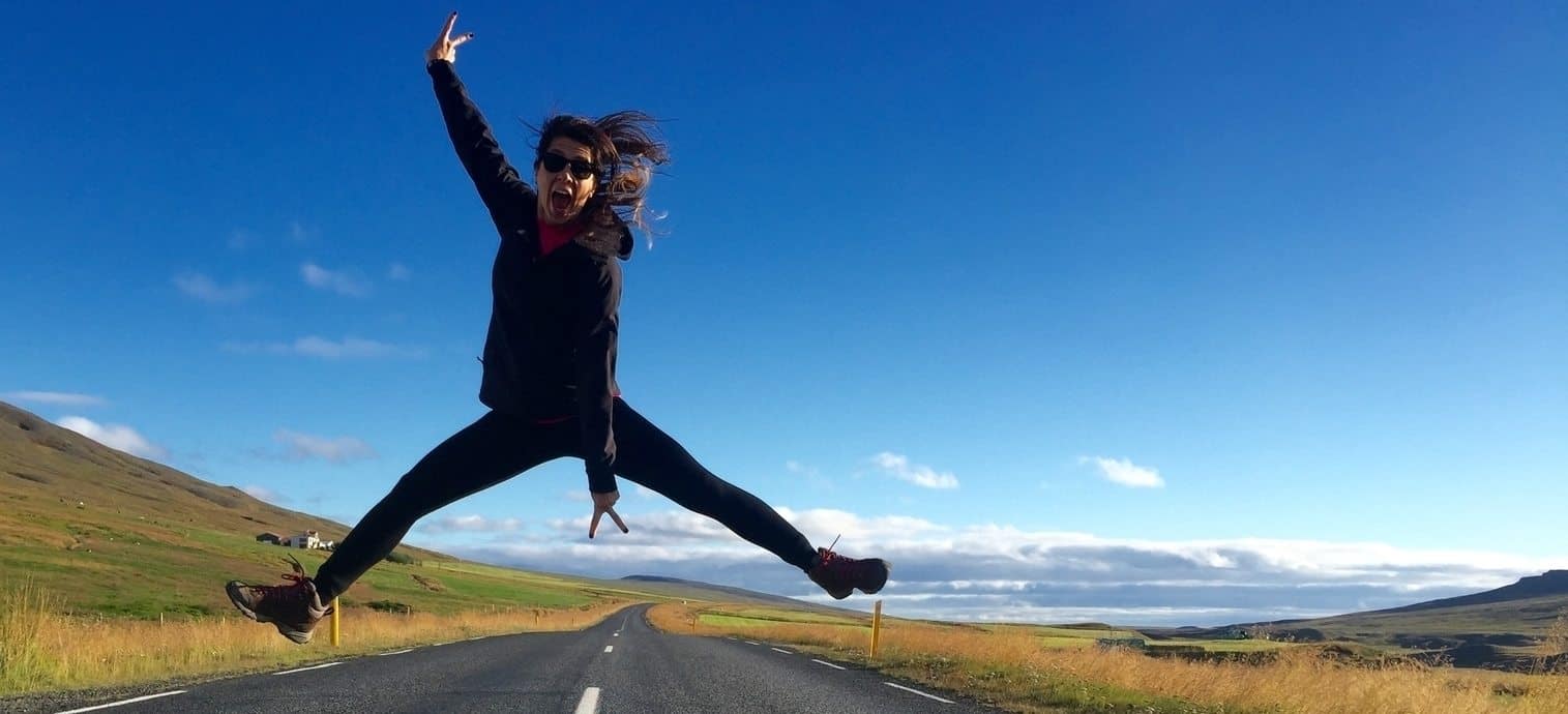 Woman jumping in the air on a road in Iceland